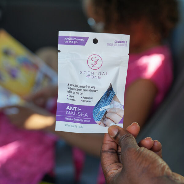 Scentral Zone's Anti-Nausea waterless essential oil diffuser held in car by child reading