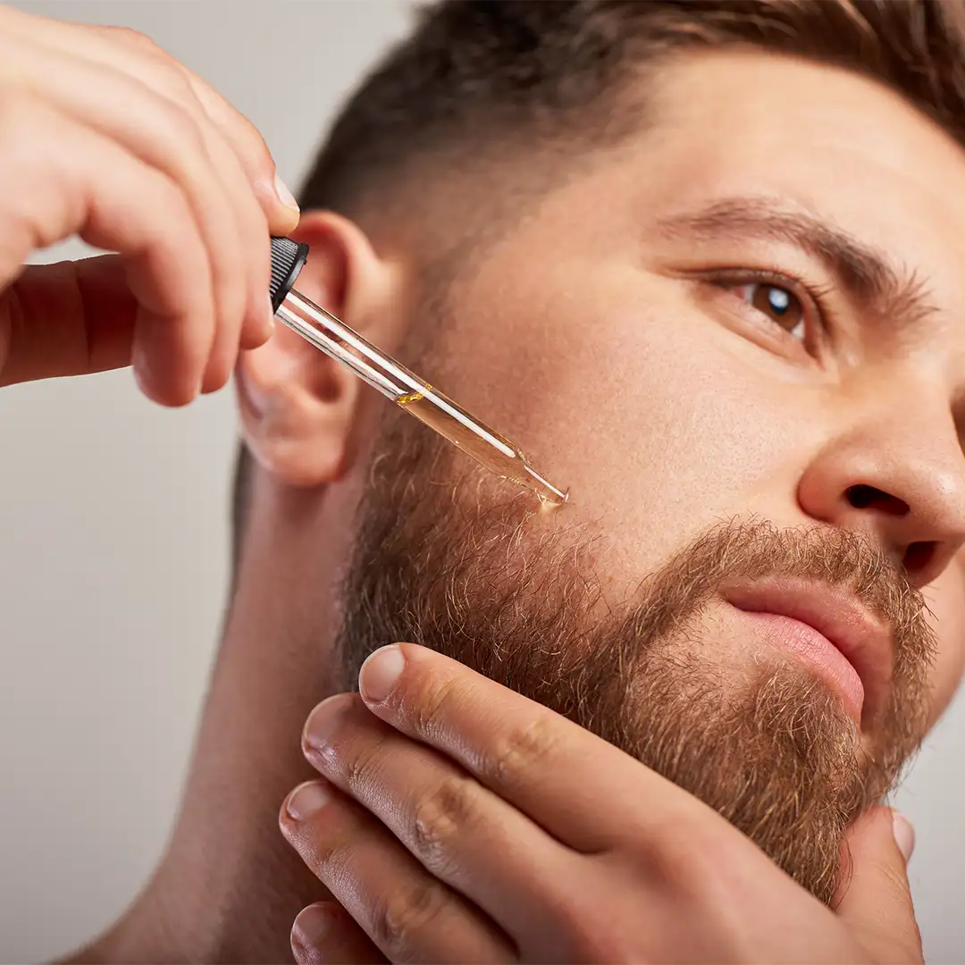 Man with beard applying beard oil to face